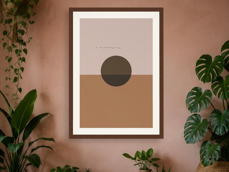 May include: A framed wall art print featuring a split-tone background with a light beige upper half and a terracotta lower half. A large, dark brown circle is centered over the horizon line, and a small flock of birds is visible in the upper section.