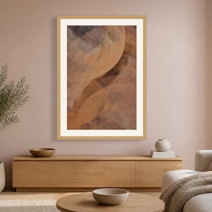 May include: A framed vertical wall art print featuring an abstract composition of flowing, layered shapes in shades of warm terracotta, soft orange, and muted charcoal gray, enclosed within a light-toned wooden frame and a wide white mat border.