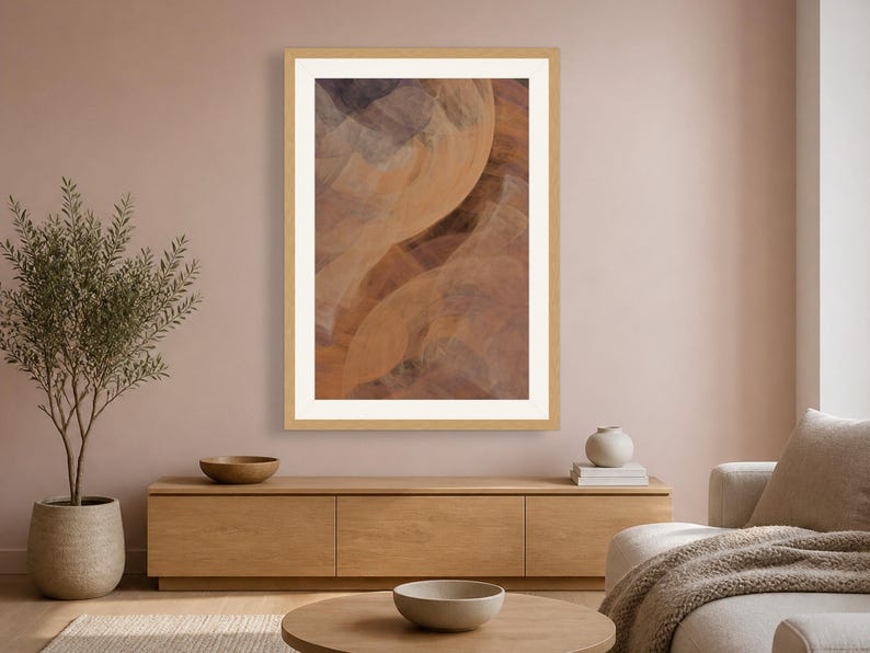May include: A framed vertical wall art print featuring an abstract composition of flowing, layered shapes in shades of warm terracotta, soft orange, and muted charcoal gray, enclosed within a light-toned wooden frame and a wide white mat border.