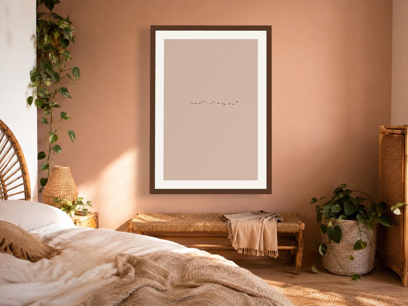 May include: A framed wall art print featuring a minimalist composition with a solid light beige background and a small, horizontal line of tiny black birds flying in the center, enclosed within a dark brown frame and a wide white mat border.