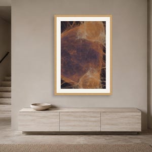 May include: A framed vertical wall art print featuring an abstract composition of wispy, glowing orange and amber filaments set against a deep, dark charcoal background, enclosed within a light-toned wooden frame and a wide white mat border.
