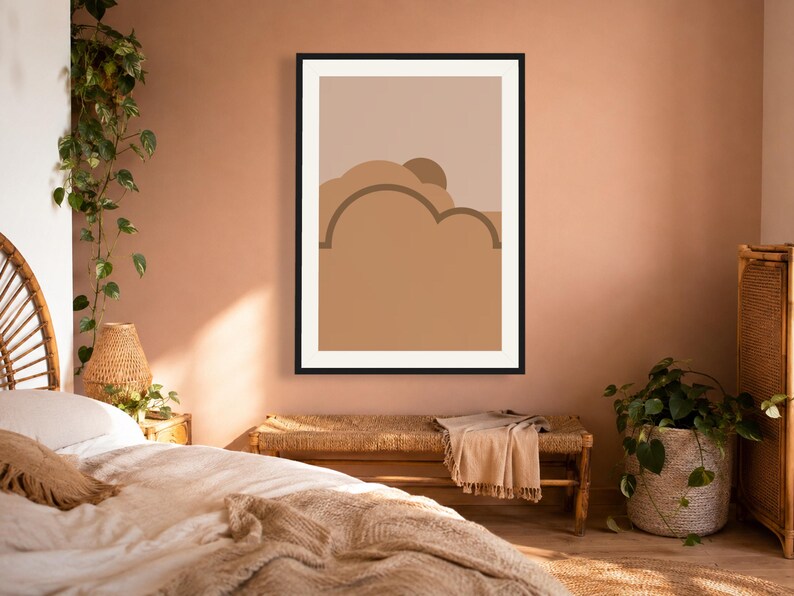 May include: A framed wall art print featuring a minimalist abstract landscape design with layered shapes in shades of tan, beige, and brown. The composition includes rounded, cloud-like forms and a semi-circular sun element set against a light background.
