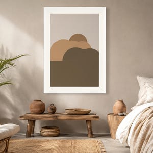 Puede incluir: Una l&aacute;mina de arte mural enmarcada que presenta una composici&oacute;n de paisaje abstracto con formas redondeadas superpuestas en tonos beige, tostado y marr&oacute;n oscuro, sobre un fondo gris claro con un borde blanco grueso.
