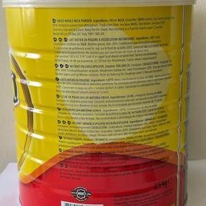 May include: A yellow and red can of dried whole milk powder with text in multiple languages. The can has a net weight of 2.5 kg and a barcode. The product is made by Nestlé.