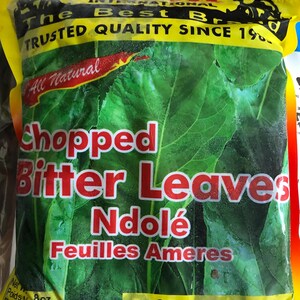 May include: A yellow and black bag of frozen chopped bitter leaves, also known as Ndolé. The bag features a red ribbon with the words "All Natural" and a picture of an elephant. The bag also includes the text "TRUSTED QUALITY SINCE 19%", "No Additives, No Preservatives, Keep Frozen" and "Net Wt. 8oz, Poids Net 227g".