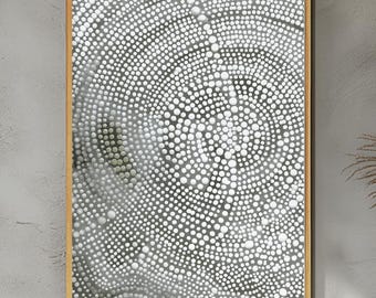 May include: Abstract art print featuring a pattern of white dots arranged in concentric circles on a gray background. The artwork is framed in a natural wood-tone frame, creating a modern aesthetic. The piece is suitable for home or office decor.