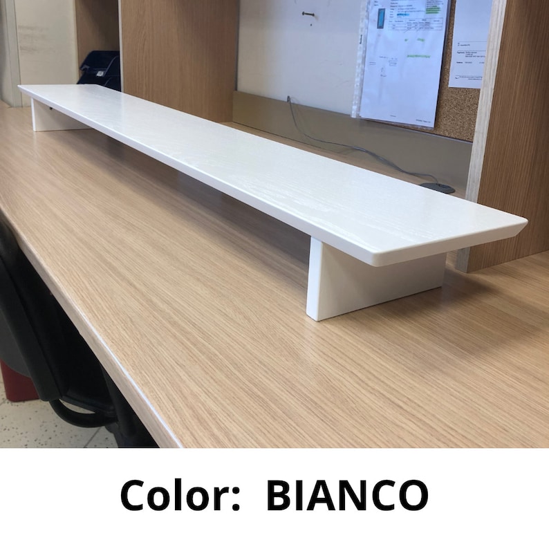 May include: White monitor stand made of wood. The stand is on a wooden desk. Color: BIANCO