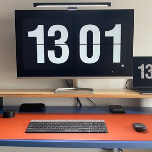 May include: A home office desk with a computer monitor, laptop, keyboard, mouse, and a cup of pens. The monitor and laptop both display the time 13:01.