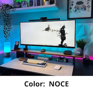 May include: A modern home office setup with a computer monitor, keyboard, mouse, and a smart speaker. The desk is made of wood and has a light blue accent light. The background is a light blue wall with a geometric pattern.