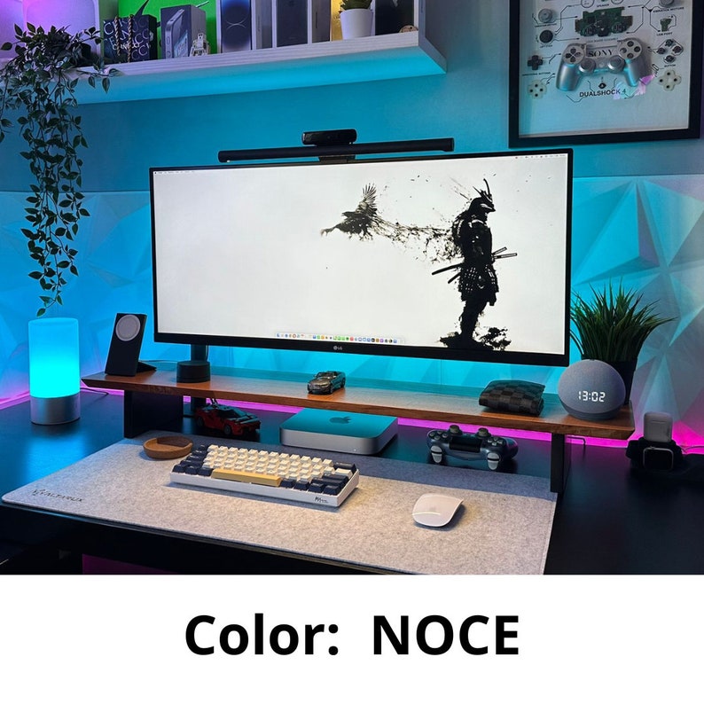 May include: A modern home office setup with a computer monitor, keyboard, mouse, and a smart speaker. The desk is made of wood and has a light blue accent light. The background is a light blue wall with a geometric pattern.