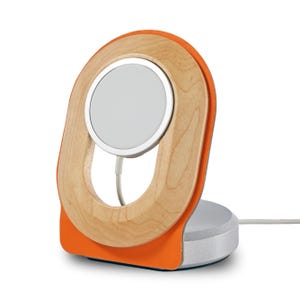 Può includere: Un moderno caricatore wireless con una cornice in legno chiaro e dettagli arancioni. Il caricatore presenta un pad di ricarica circolare e una base argentata. Il design è elegante e contemporaneo, con un cavo di ricarica bianco.