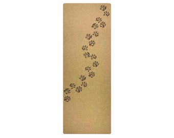May include: A brown cork yoga mat with a pattern of black paw prints. The paw prints are scattered across the mat in a curved line.