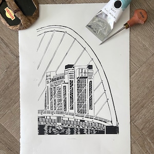 May include: Black and white linocut print of a bridge with a large arch and a building with the text "BANK OF ENGLAND" on the side.
