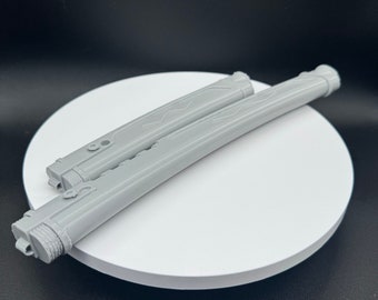May include: Two light gray, cylindrical, elongated objects with a smooth, matte finish. Each piece features a series of linear indentations, a small circular protrusion near one end, and a textured, ridged cap at the base of the main body.