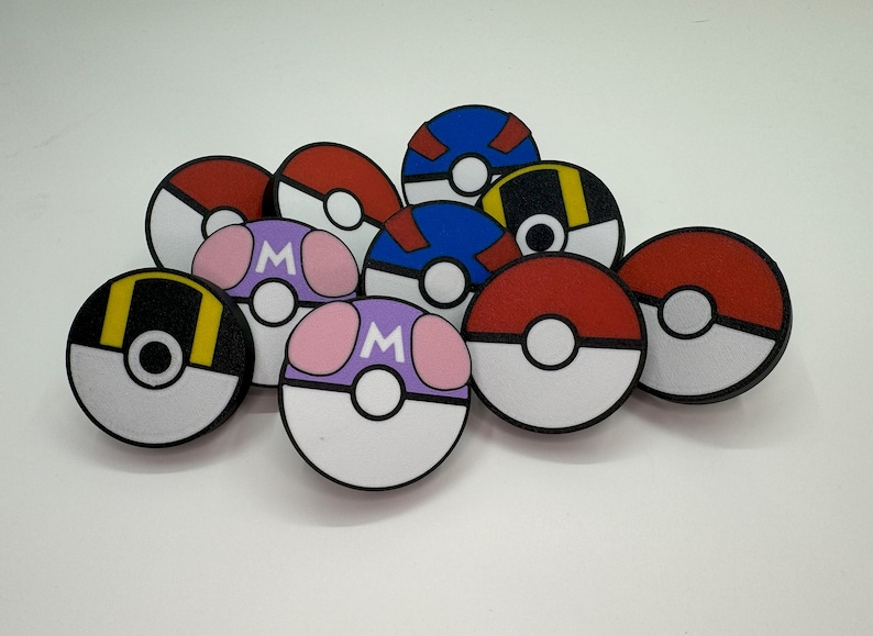 Puede incluir: Una colecci&oacute;n de dise&ntilde;os redondos y coloridos de estilo caricatura que se asemejan a Pok&eacute; Balls. Los dise&ntilde;os presentan varios esquemas de color, incluyendo rojo y blanco, azul y blanco, y morado con acentos rosas. Algunos tienen una "M".