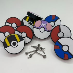 Puede incluir: Una colecci&oacute;n de pomos de armario redondos y coloridos con varios dise&ntilde;os, incluyendo rojo y blanco, negro y amarillo, y morado con la letra "M". Tambi&eacute;n se ven varios tornillos plateados, lo que sugiere que est&aacute;n listos para la instalaci&oacute;n.