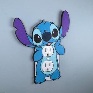 May include: A blue and purple Stitch character wall plate cover with two standard US electrical outlets.