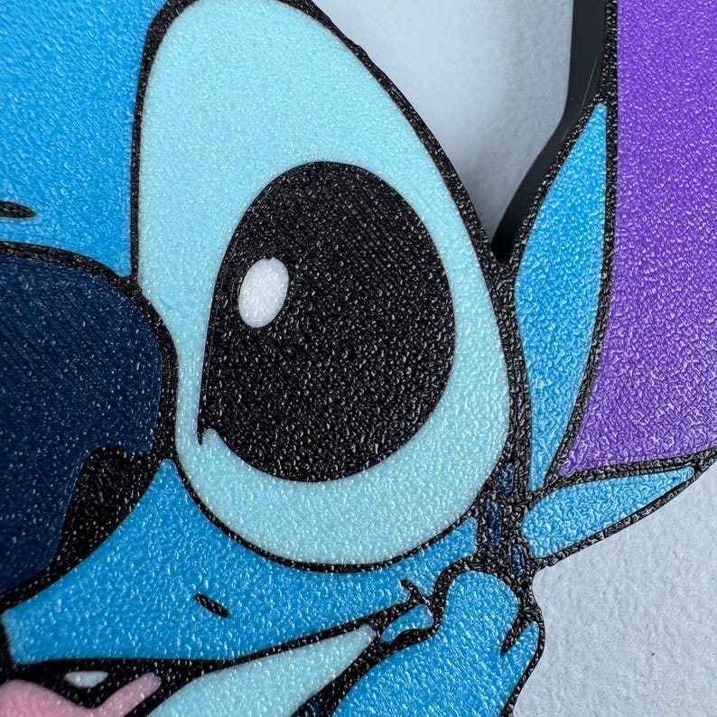 May include: Close-up of a blue and purple cartoon character with one large black eye and a white highlight. The character has a textured surface.