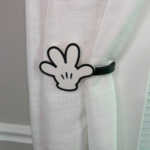 May include: White Mickey Mouse hand shaped curtain tie back with a black strap.