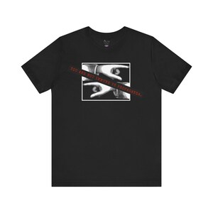 May include: Black t-shirt featuring a graphic of two hands with the text "YOU ARE NOT IMMUNE TO PROPAGANDA." The hands are in a black and white image inside a white rectangle. The text is in red and is diagonally across the image.