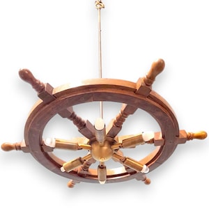 May include: A nautical-themed chandelier in the shape of a ship's wheel. The wheel is made of dark brown wood with six spokes and six wooden handles. The center features brass-colored light fixtures with six bulbs.