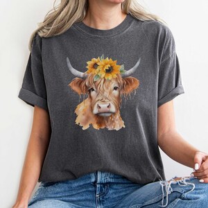 May include: A gray t-shirt with a watercolor illustration of a brown and white cow wearing a sunflower crown.