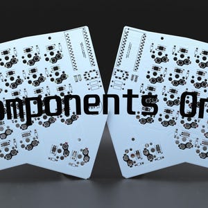 May include: Two light blue printed circuit boards with black electronic component footprints and traces, featuring the text Components Only printed in black across the center of both boards, arranged side by side on a dark background.