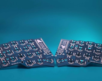 Puede incluir: Dos placas de circuito impreso de color azul oscuro para un teclado mecánico dividido. Cada placa presenta una rejilla de zócalos circulares para interruptores, etiquetas impresas en blanco y el texto "crkbd" con un logotipo.