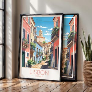 May include: A framed art print depicting a narrow street in Lisbon, Portugal, with colorful pink and blue buildings, balconies with green plants, and a stone path under a blue sky. The text LISBON Portugal is printed in pink at the bottom.