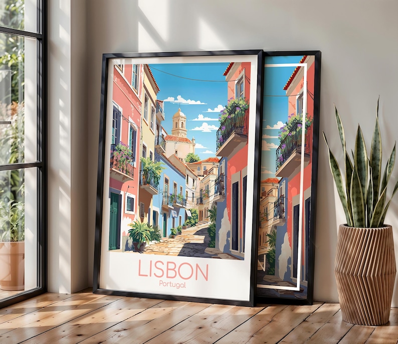 May include: A framed art print depicting a narrow street in Lisbon, Portugal, with colorful pink and blue buildings, balconies with green plants, and a stone path under a blue sky. The text LISBON Portugal is printed in pink at the bottom.