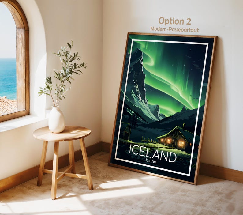 May include: A framed art print featuring a landscape of Iceland under the aurora borealis. The artwork showcases a cabin with lit windows, mountains, and the text "ICELAND Island" in white. The frame is brown.