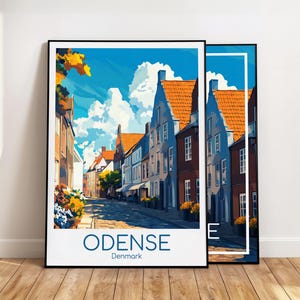 Puede incluir: Dos láminas enmarcadas de una escena callejera en Odense, Dinamarca. La obra de arte representa edificios coloridos con tejados naranjas y una calle adoquinada bajo un cielo azul con nubes. La palabra "ODENSE" y "Denmark" están impresas en la parte inferior.