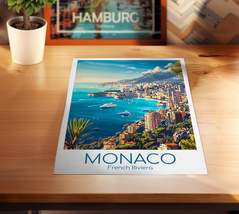 Puede incluir: Una impresi&oacute;n de M&oacute;naco, Riviera Francesa, que muestra una ciudad costera con edificios, barcos y un mar azul bajo un cielo brillante. La palabra "MONACO" est&aacute; impresa en azul en la parte inferior de la impresi&oacute;n.