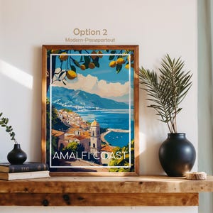 Pu&ograve; includere: Una stampa d'arte incorniciata con un'illustrazione colorata della Costiera Amalfitana, limoni gialli in primo piano, un mare blu e una citt&agrave; costiera con un campanile. Il testo in basso riporta "AMALFI COAST" e "Italy".