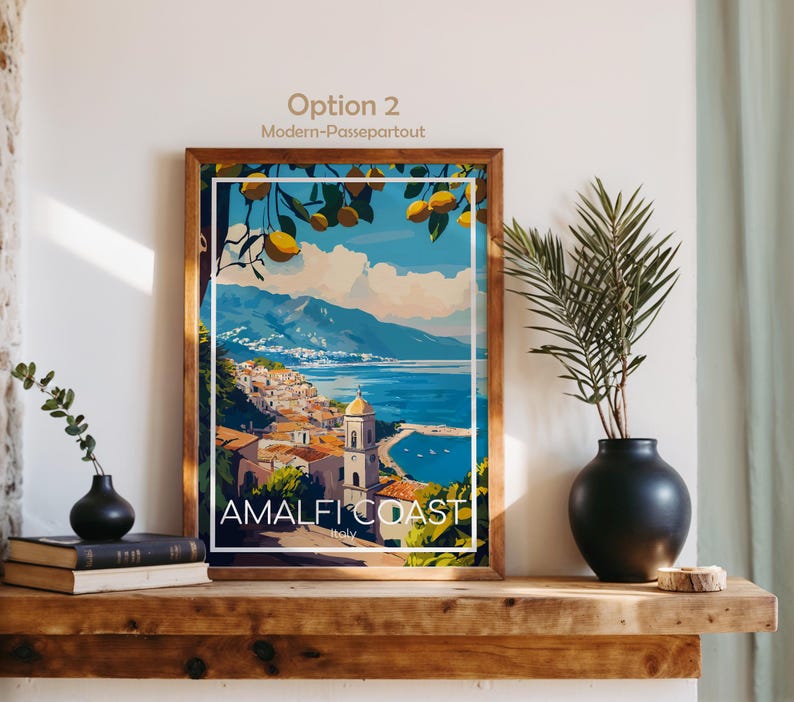 Pu&ograve; includere: Una stampa d'arte incorniciata con un'illustrazione colorata della Costiera Amalfitana, limoni gialli in primo piano, un mare blu e una citt&agrave; costiera con un campanile. Il testo in basso riporta "AMALFI COAST" e "Italy".