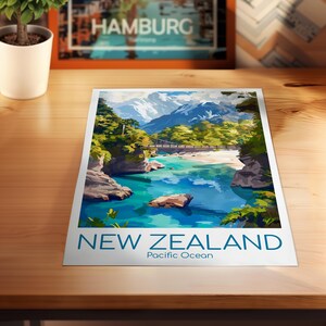 Puede incluir: Una impresi&oacute;n art&iacute;stica rectangular que presenta una vibrante ilustraci&oacute;n paisaj&iacute;stica de Nueva Zelanda con agua turquesa, costas rocosas, &aacute;rboles verdes exuberantes y monta&ntilde;as nevadas. El texto NEW ZEALAND y Pacific Ocean est&aacute; impreso en azul en la parte inferior.