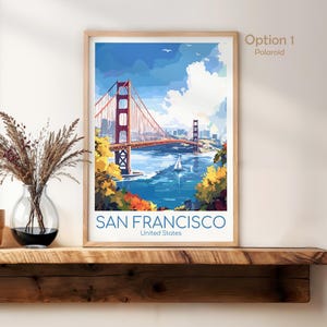 May include: A framed art print of the Golden Gate Bridge in San Francisco. The artwork features the bridge in a watercolor style, with blue water, a sailboat, and the text "SAN FRANCISCO United States".