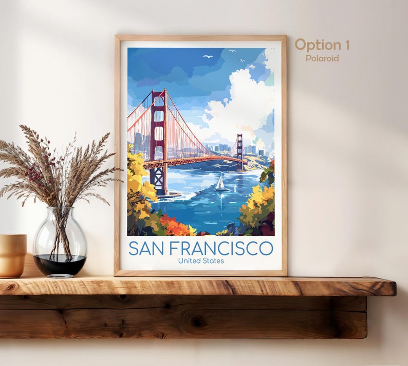 May include: A framed art print of the Golden Gate Bridge in San Francisco. The artwork features the bridge in a watercolor style, with blue water, a sailboat, and the text "SAN FRANCISCO United States".