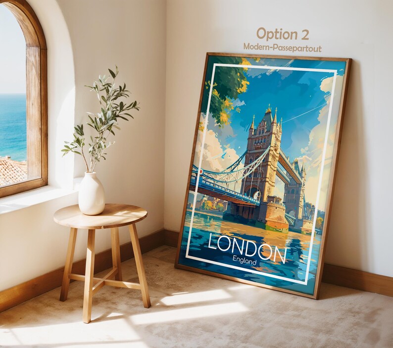 May include: A framed art print featuring the Tower Bridge in London, England, with a blue sky and water. The print has a white border and a wooden frame. The word "LONDON" is displayed prominently at the bottom.