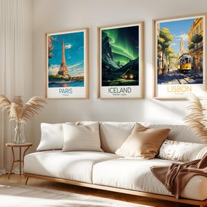 May include: Three framed travel art prints. The prints feature iconic locations: Paris with the Eiffel Tower, Iceland with the Northern Lights, and Lisbon with a yellow tram. The prints are displayed above a white sofa.