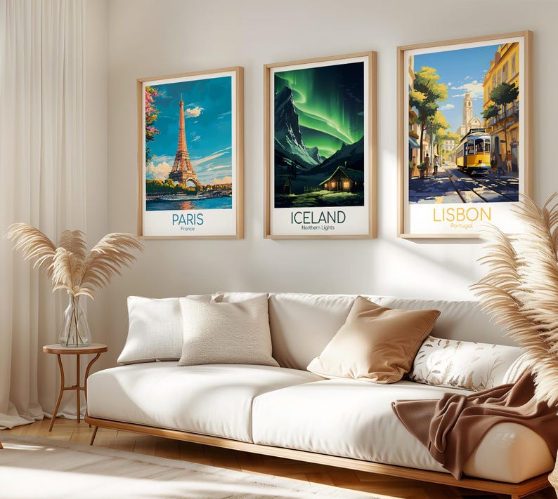 May include: Three framed travel art prints. The prints feature iconic locations: Paris with the Eiffel Tower, Iceland with the Northern Lights, and Lisbon with a yellow tram. The prints are displayed above a white sofa.