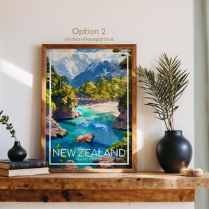 Puede incluir: Una l&aacute;mina art&iacute;stica enmarcada con una ilustraci&oacute;n paisaj&iacute;stica de Nueva Zelanda con monta&ntilde;as nevadas, un puente colgante sobre un r&iacute;o turquesa y &aacute;rboles verdes. El texto en la parte inferior dice NEW ZEALAND Pacific Ocean.
