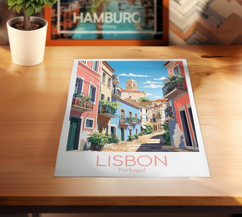 May include: A rectangular art print featuring a colorful illustration of a narrow street in Lisbon, Portugal. The scene depicts pastel-colored buildings with balconies, green plants, and a stone path under a blue sky. The text LISBON Portugal is printed below.