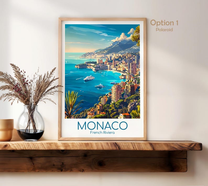 Puede incluir: Una impresi&oacute;n art&iacute;stica enmarcada de M&oacute;naco, Riviera Francesa. La obra de arte representa una ciudad costera con edificios, barcos y un mar azul bajo un cielo brillante. La impresi&oacute;n est&aacute; etiquetada como "MONACO" y "French Riviera" en azul.