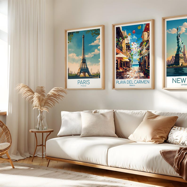 K&ouml;nnte beinhalten: Drei gerahmte Kunstdrucke mit Reise-Motiven, die ber&uuml;hmte Wahrzeichen zeigen: den Eiffelturm in Paris, eine Stra&szlig;enszene in Playa del Carmen und die Freiheitsstatue in New York. Jeder Druck hat einen hellen Holzrahmen und einen wei&szlig;en Rand, &uuml;ber einem wei&szlig;en Sofa.
