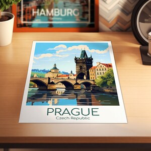 Puede incluir: Un cartel de viaje vintage con una ilustraci&oacute;n colorida del Puente Carlos en Praga, Rep&uacute;blica Checa. El puente es un puente de arco de piedra con una torre en un lado. El cartel tiene un cielo azul con nubes blancas y un r&iacute;o que refleja el puente.