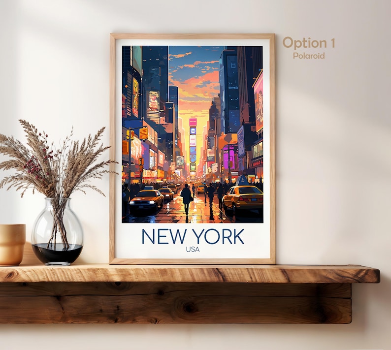 May include: A framed vertical art print featuring a vibrant illustration of a New York City street scene at sunset with yellow taxis, tall buildings, and glowing billboards. The text NEW YORK USA is printed in dark blue at the bottom of the white border.