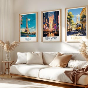 May include: Three framed vertical art prints hanging on a wall, each depicting a city scene. The left print shows the Eiffel Tower in Paris, the center print displays a busy New York City street at sunset, and the right print features a yellow tram in Lisbon.