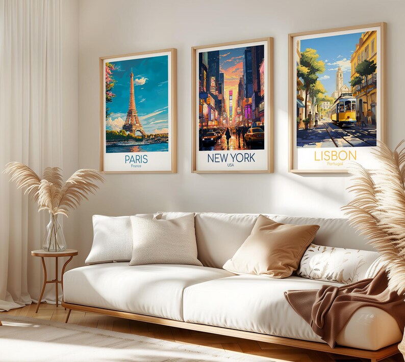 May include: Three framed vertical art prints hanging on a wall, each depicting a city scene. The left print shows the Eiffel Tower in Paris, the center print displays a busy New York City street at sunset, and the right print features a yellow tram in Lisbon.