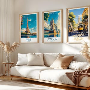 May include: Three framed travel art prints featuring iconic landmarks: the Eiffel Tower in Paris, Tower Bridge in London, and a yellow tram in Lisbon. Each print has a light wood frame and a white border, with the city name below.
